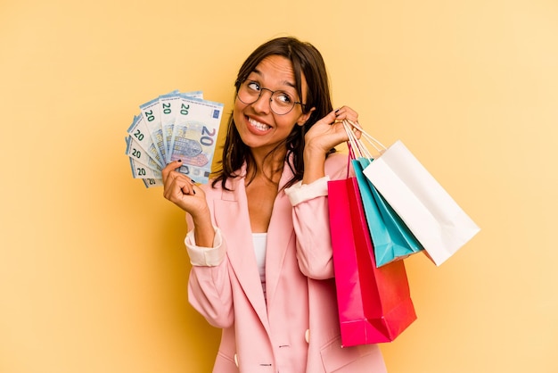 Young hispanic woman holding shopping bag isolé sur fond jaune