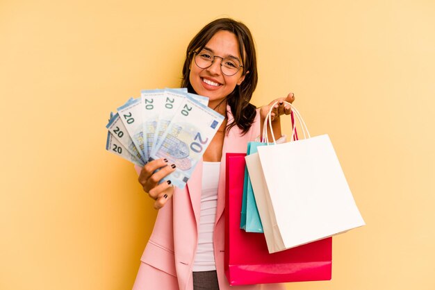 Young hispanic woman holding shopping bag isolé sur fond jaune