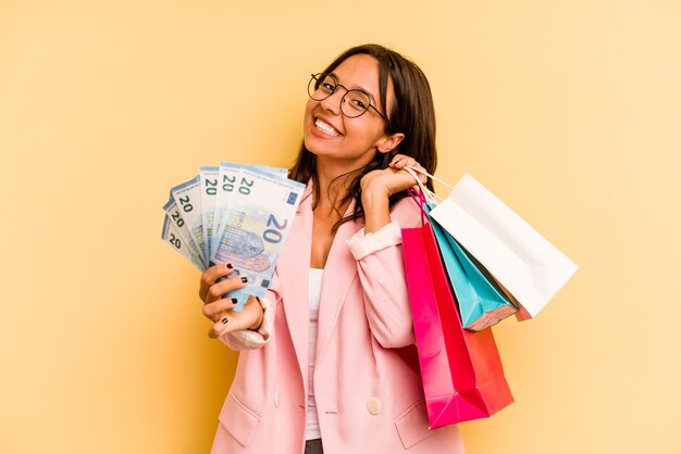 Young hispanic woman holding shopping bag isolé sur fond jaune