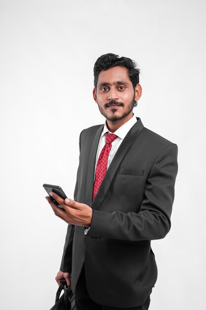 Young Indian Businessman holding sac d'ordinateur portable à la main et à l'aide de mobile