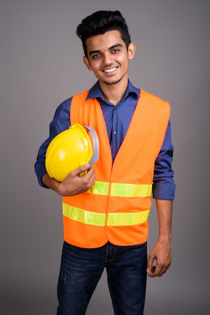 Young Indian man construction worker contre mur gris