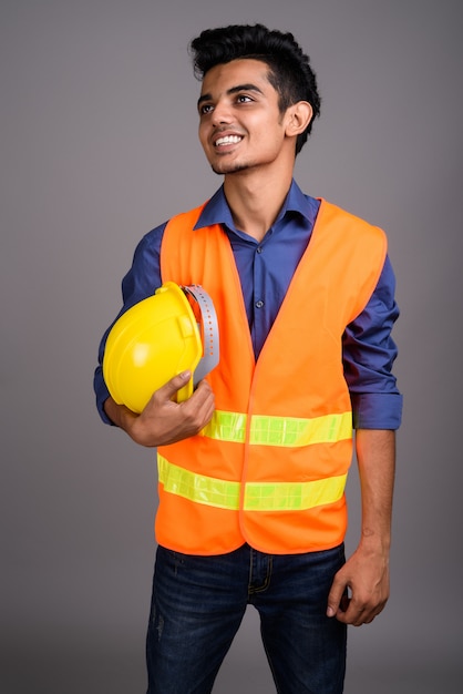 Young Indian man construction worker contre mur gris