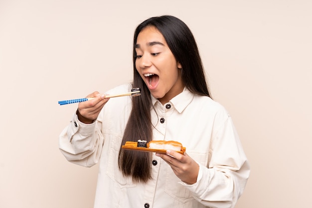 Young Indian woman holding sushi isolé sur fond beige