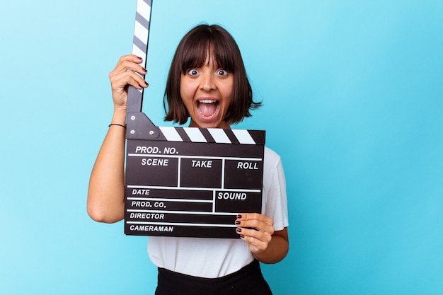 Young mixed race woman holding a clapper board