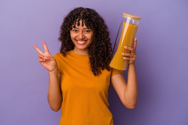 Young mixed race woman holding spaghetti isolé sur fond violet montrant le numéro deux avec les doigts.