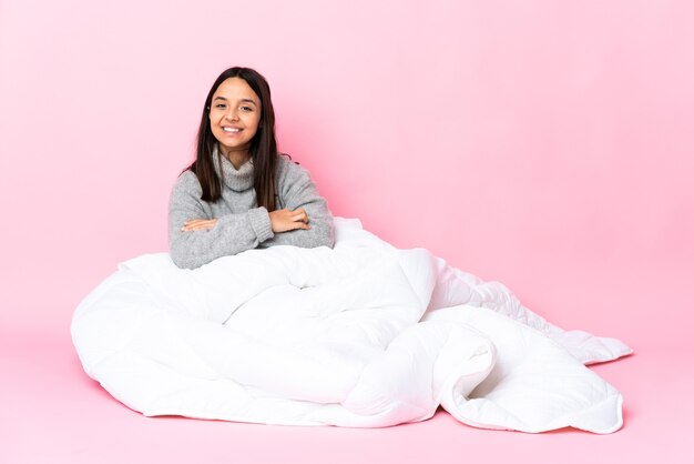 Young mixed race woman wearing pijama assis sur le sol avec les bras croisés et impatient