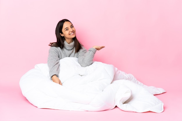 Young mixed race woman wearing pijama assis sur le sol