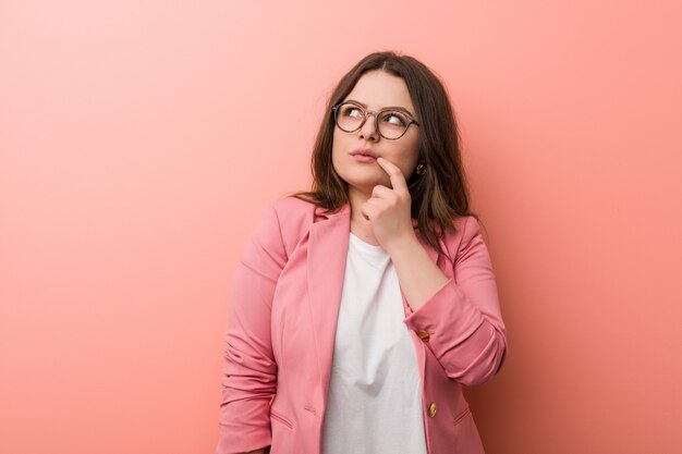 Young plus size business caucasian woman looking sideways avec une expression douteuse et sceptique.