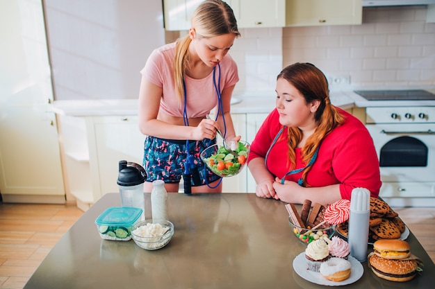 Ypung femme mince montre bol modèle en surpoids avec slaad. Tenez-vous dans la cuisine.