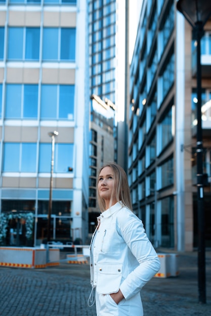 Yuong femme en costume blanc se promenant dans la ville