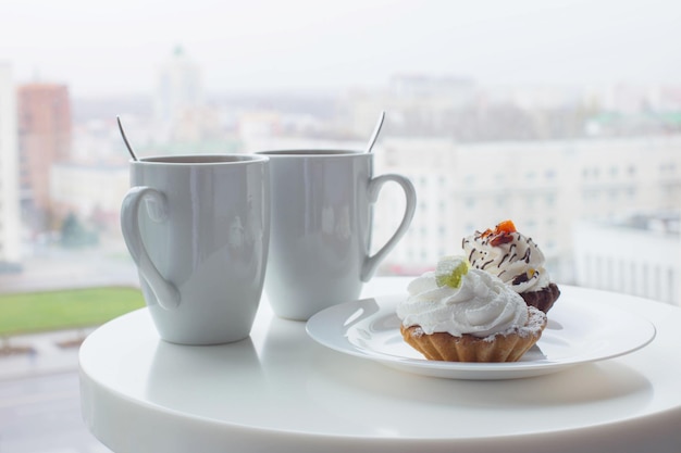 Ywo cupcakes et deux tasses sur table au café