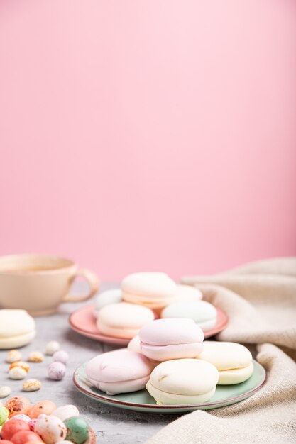 Zéphyr coloré ou guimauve avec tasse de café et dragées sur fond gris et rose.