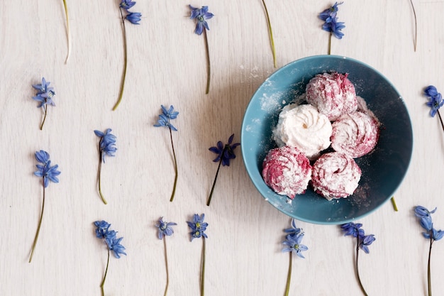 Zéphyr. Photographie culinaire créative. Bonbons colorés dans une assiette turquoise sur les fleurs de printemps