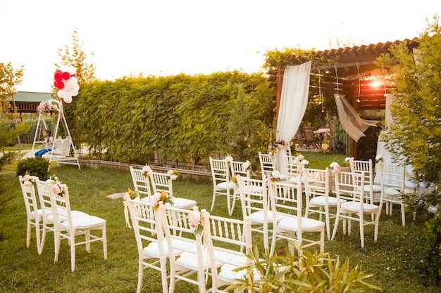 Zone de cérémonie vide Décor de fleurs et allée de verdure Chaises blanches Belle décoration florale du lieu du mariage et détails de la cérémonie