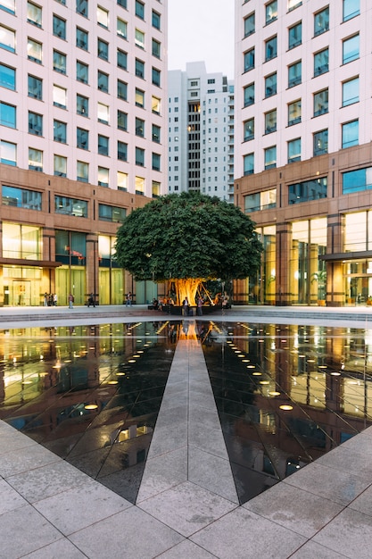 Zone de la fontaine de l&#39;espace urbain avec grand arbre vert dans le coin avec les gens.