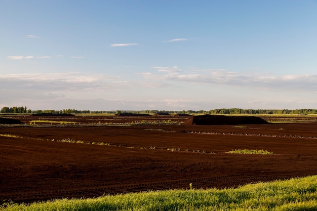 Photo zone industrielle où l'extraction est effectuée dans la tourbe noire. photo avec une petite profondeur de champ. saison d'été, ciel bleu en arrière-plan