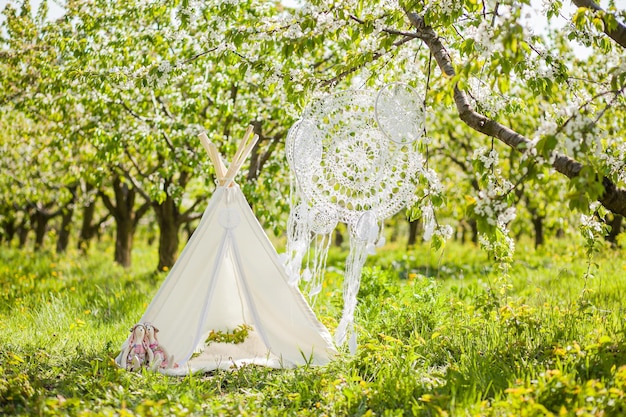 Zone photo pour une séance photo d'enfants dans un jardin fleuri au printemps wigwam attrape-rêves au crochet et jouets pour lapins