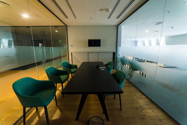 Zone de réunion dans le bureau dans un style loft avec des murs en briques blanches et des colonnes en béton La zone a une grande table en bois avec des chaises grises et des cloisons en verre