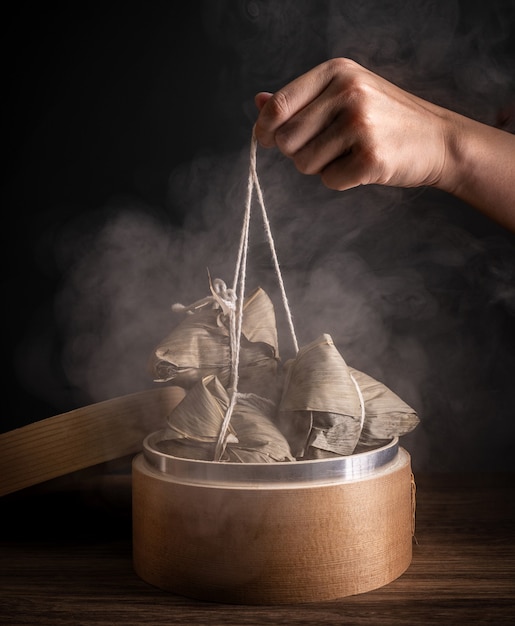 Zongzi, femme va manger des boulettes de riz cuit à la vapeur sur la table en bois, célèbre nourriture savoureuse dans le concept de design de festival de bateaux-dragons duanwu, gros plan, espace copie