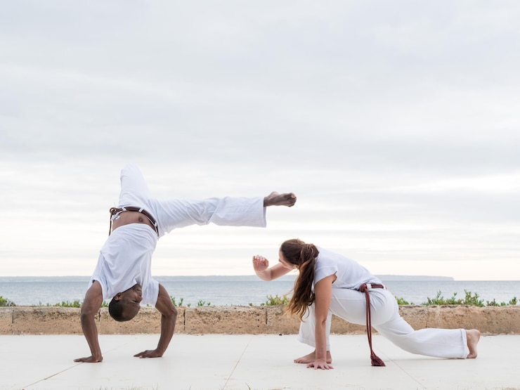 Foto a couple doing capoeira exercise near an ocean view