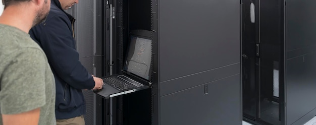A couple of server engineers cooperate in high tech data centers. Technicians team updating hardware inspecting system performance in super computer server room or cryptocurrency mining farm.