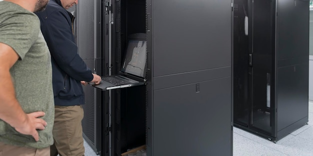 A couple of server engineers cooperate in high tech data centers. Technicians team updating hardware inspecting system performance in super computer server room or cryptocurrency mining farm.