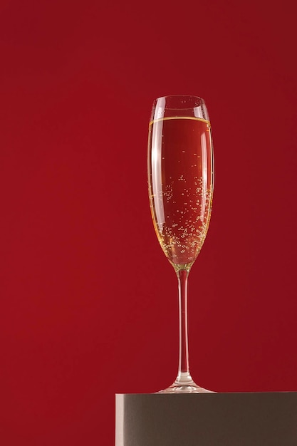 A glass of champagne on a stand on a red background holiday and new year concept