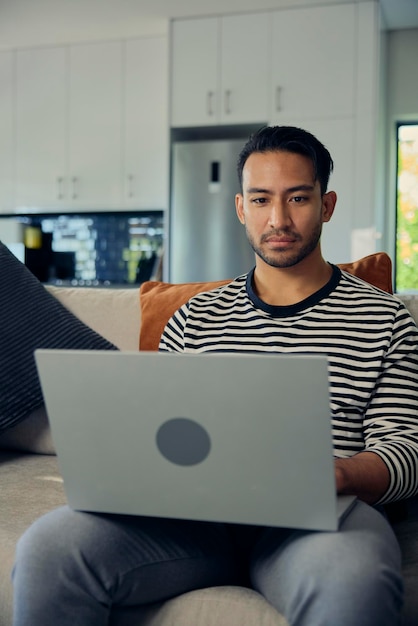 A man is comfortably sitting on a couch using a laptop computer
