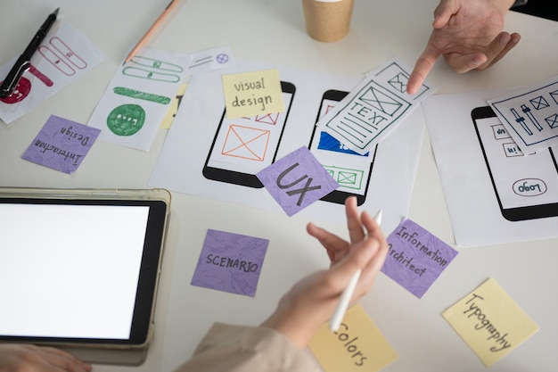 a meeting table with a graphic designer team and various prototype for a new mobile application