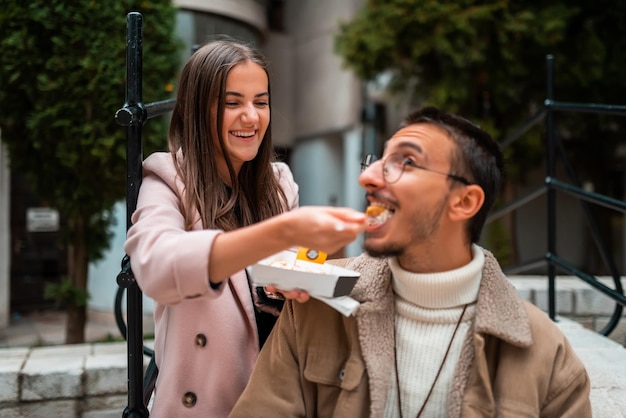 A photo of a modern man and woman enjoying the city and eating delicious fresh poffertjes High quality photo