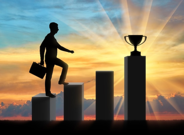 A silhouette of a businessman going up the steps to the trophy. The business concept of purpose