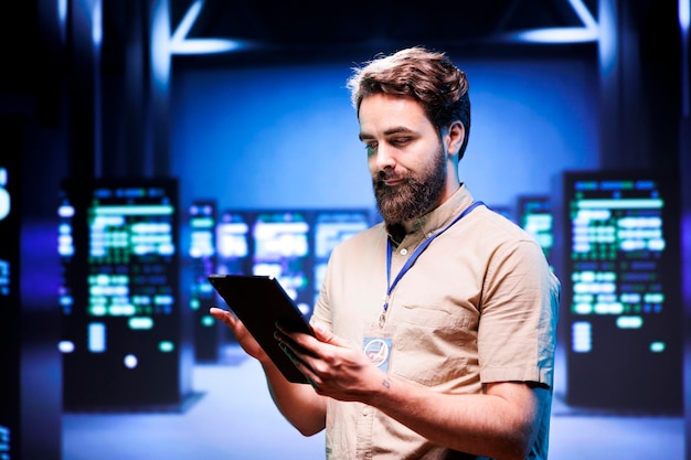 administrator in front of server rackmounts delivering web content to clients over the internet. manager in high tech facility using tablet to make sure critical systems are in faultless condition