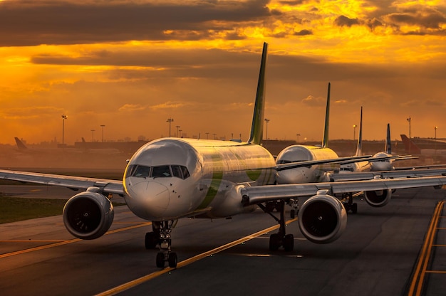 Airplane on airport runway against sky during sunset