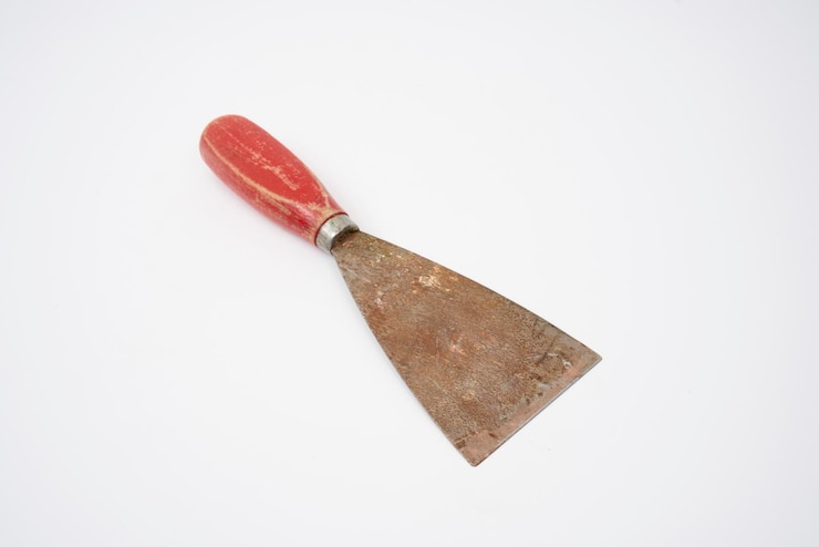 Foto an old putty knife with a red handle on an isolated white background