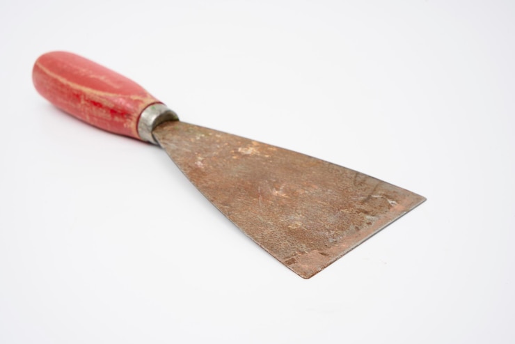Foto an old putty knife with a red handle on an isolated white background