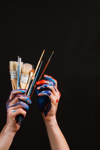 Art hobby leisure lifestyle Artist hands closeup Smeared with paint holding paintbrushes Project in process Tools selection