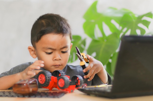 Asian boy students learn at home in coding robot cars and electronic board cables in STEM STEAM mathematics engineering science technology computer code in robotics for kids concept