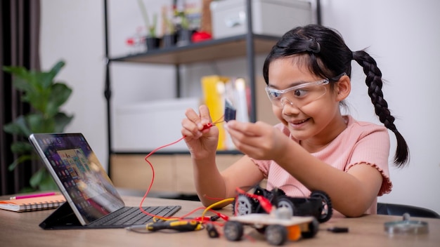 Asian students learn at home by coding robot cars and electronic board cables in STEM STEAM mathematics engineering science technology computer code in robotics for kids' concepts