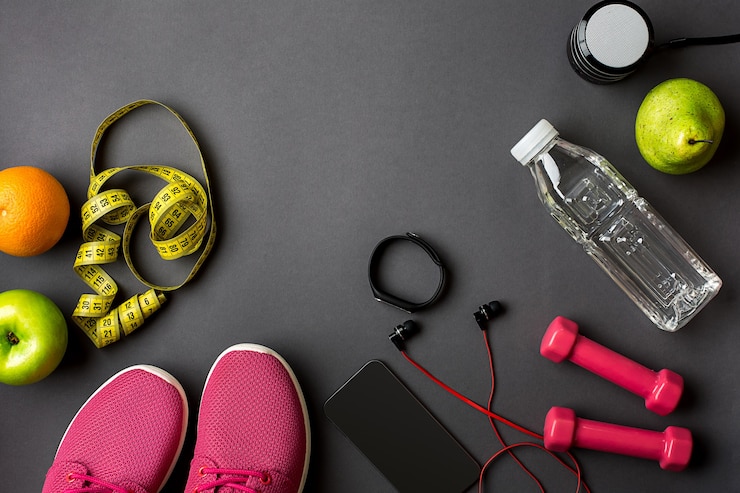 Foto athletes set with female clothing and bottle of water on dark gray background