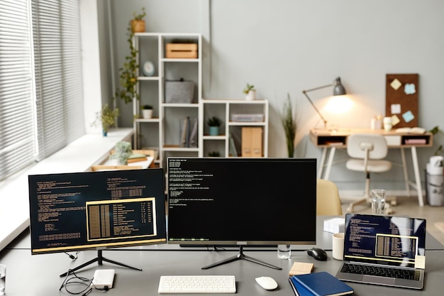 background image of it developers office with code on two computer screens and devices copy space