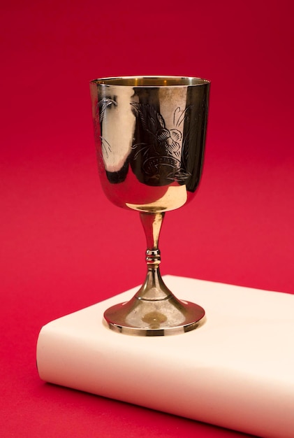 beautiful golden chalice on light beige bible with red background