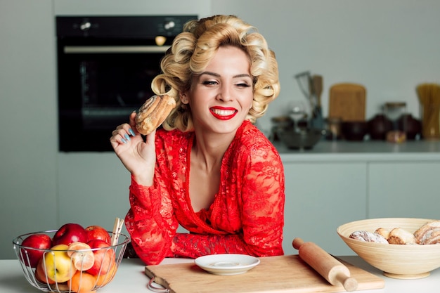 Beautiful housewife in a red robe with a bun in her hands