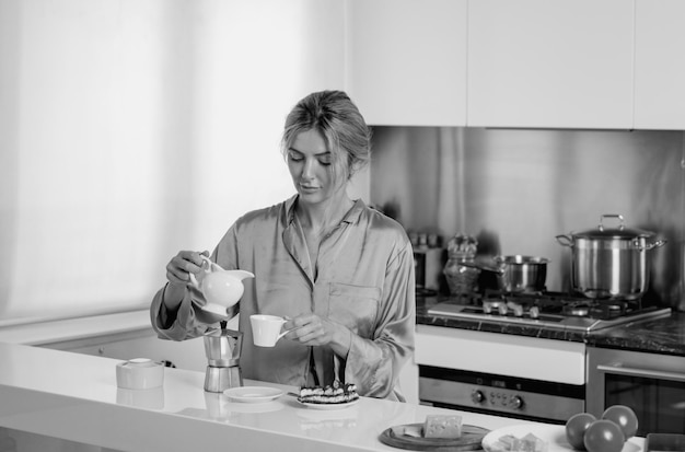 Beautiful woman pouring milk in coffee near table on kitchen at home Housewife on the kitchen in the morning