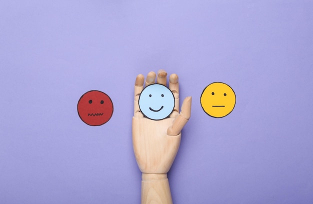 Best service Customer satisfaction survey concept Hand chooses Happy face icon neutral and sad face paper icon on violet background Top view