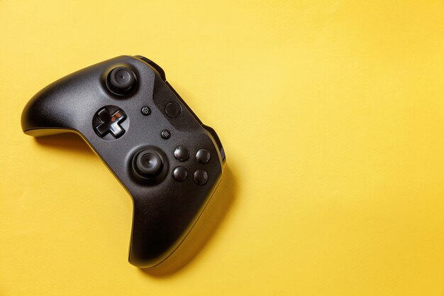 Black joystick gamepad, game console on yellow background. Computer gaming play videogame control concept
