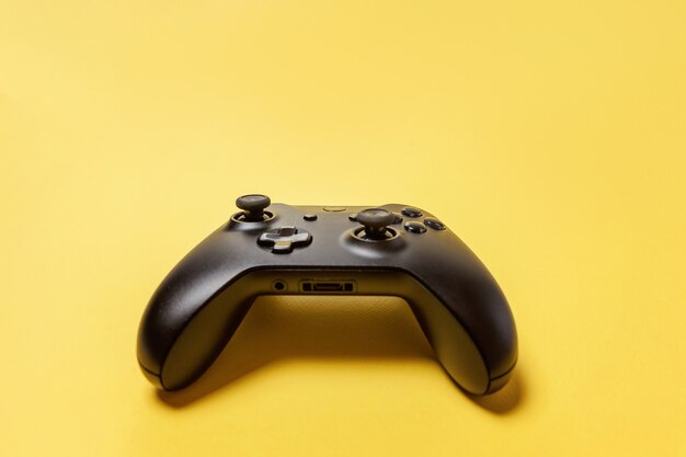 Black joystick gamepad, game console on yellow