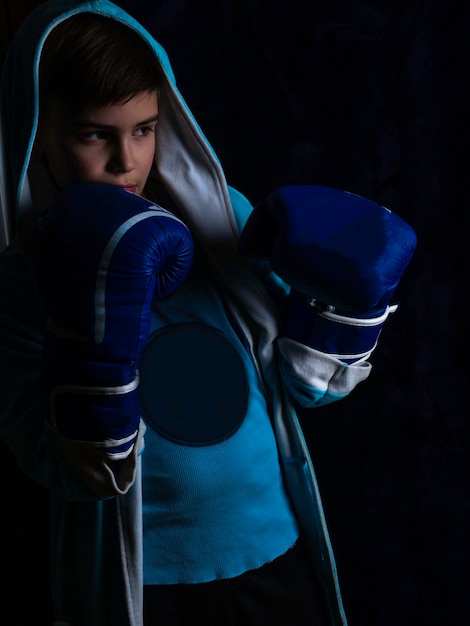 Boy in boxing gloves The defend position portrait on the black background low key lighting