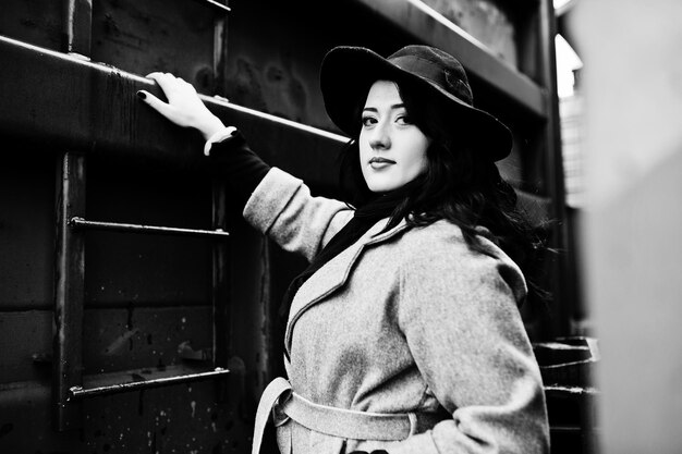 Brunette girl in gray coat with hat in railway station
