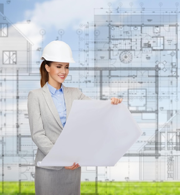 building, developing, consrtuction and architecture concept - friendly young smiling architect in white helmet with blueprints
