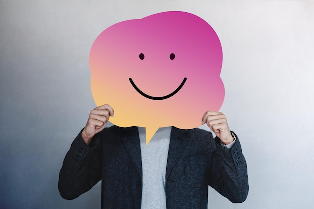 Businessman holding speech bubble anthropomorphic face against gray background